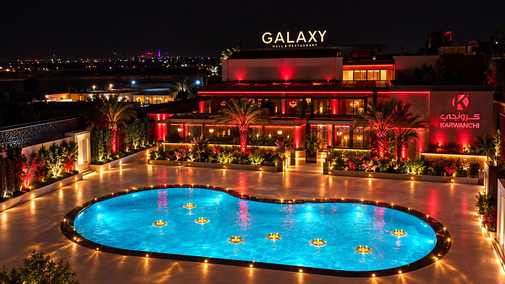Galaxy Hall and Restaurant at night, lit red, with the Karwanchi sign and the pool terrace