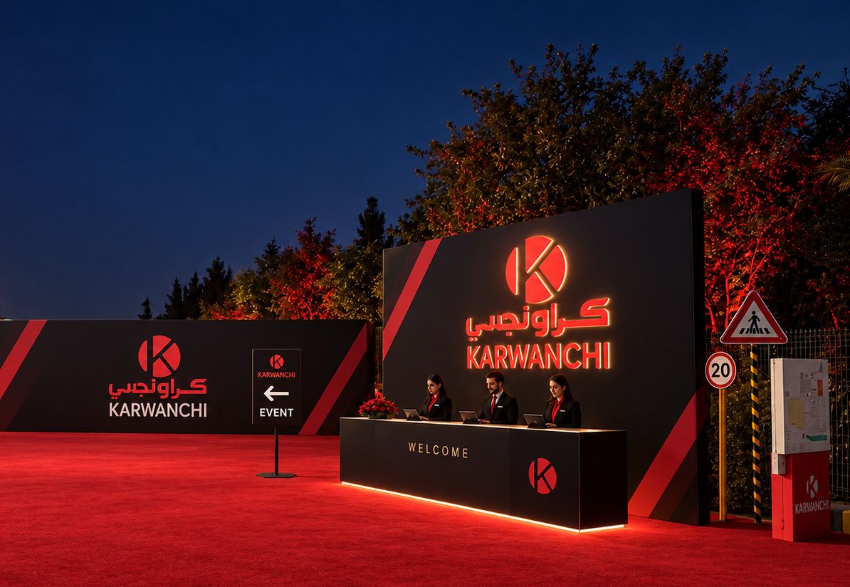 Reception backdrop with a halo-lit Karwanchi logo and a three-person welcome counter